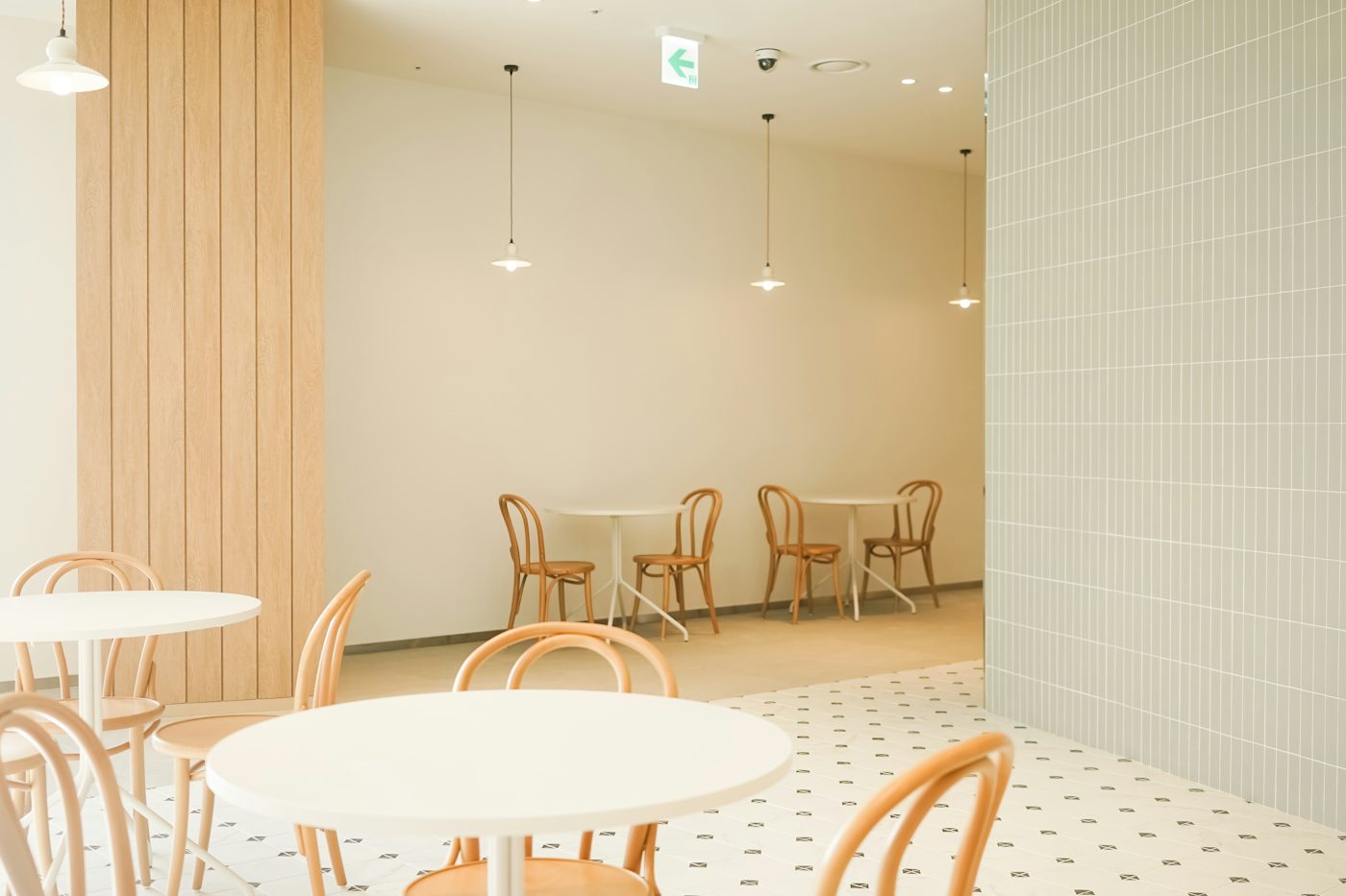 The café room: round white tables, bentwood chairs and pale green tiles