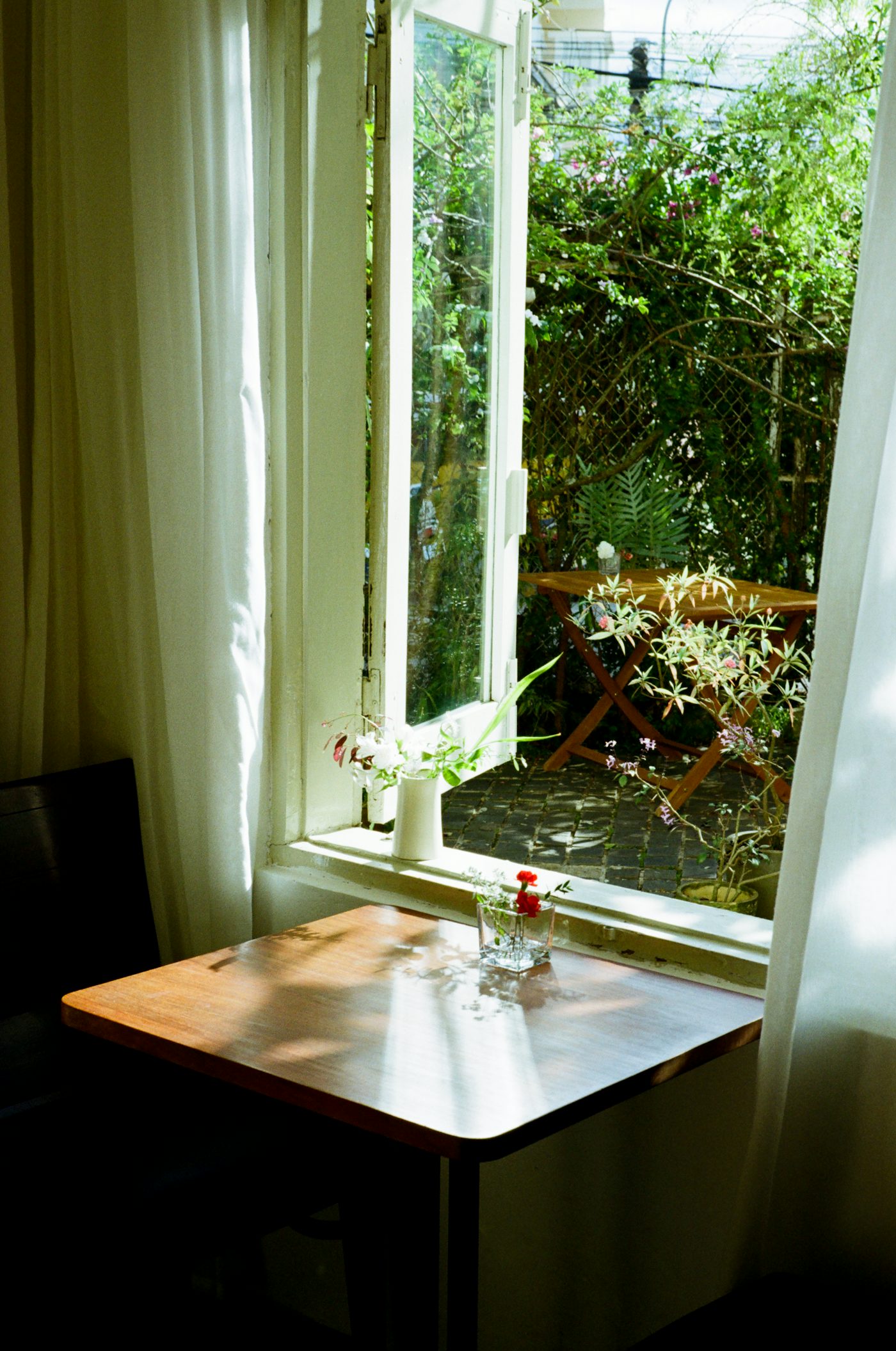 A wooden table by an open window onto the yard